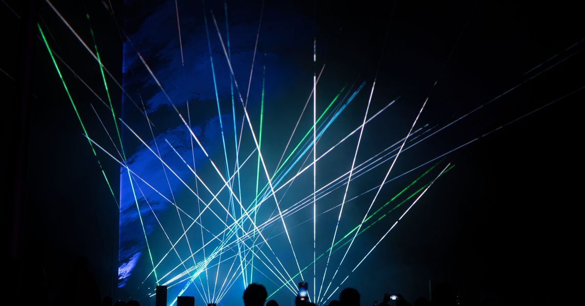 Vibrant laser show with green and blue lights captivating audience.